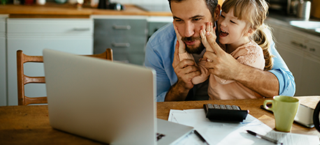 Father and daughter at kitchen table with laptop