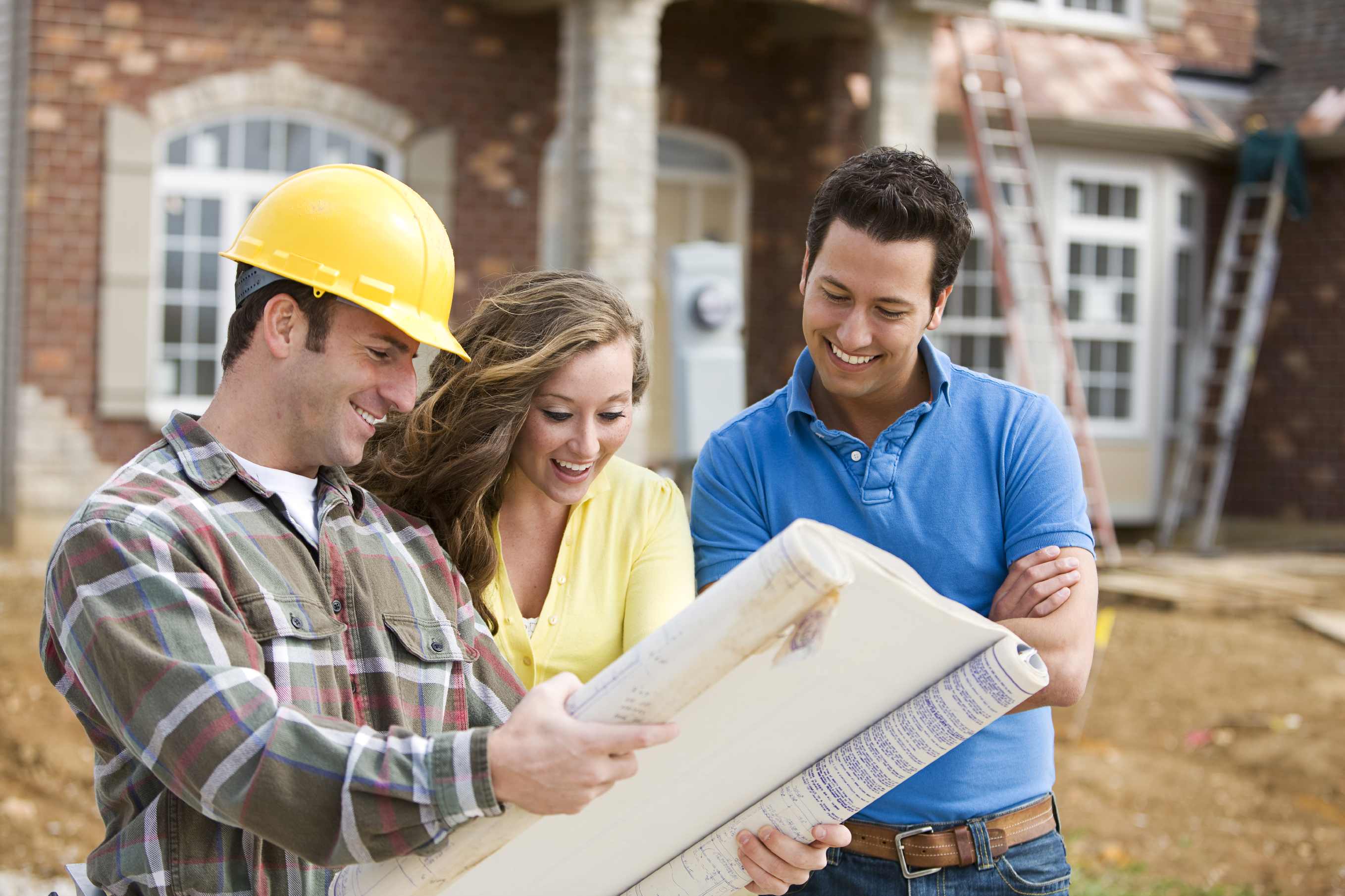 Builder in hard had with couple looking at blue prints